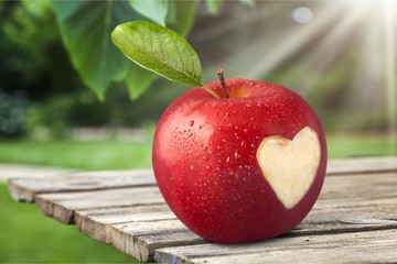 Red apple with a heart shaped cut-out. on backgrouund