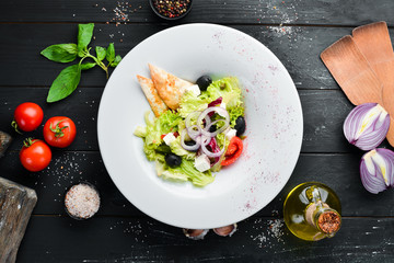 Greek salad. Vegetable salad with feta cheese, olives and cherry tomatoes. In the plate. Top view. Free space for your text. Rustic style.