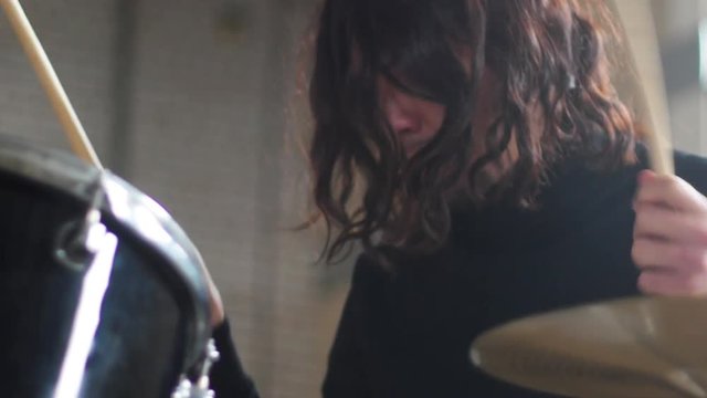 A man with long hair playing drums at repetition