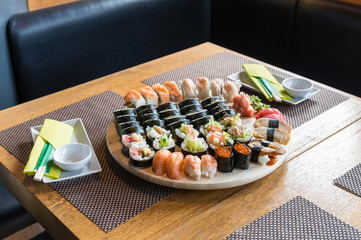 Sushi set rolls served on wooden round tray. Restaurant background