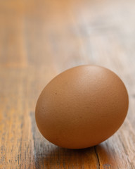 ein braunes Hühnerei liegt auf einem Holztisch