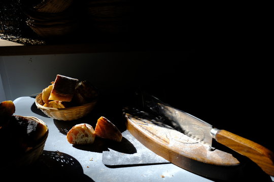 Breadboard, knife and bread on a table in the sunlight