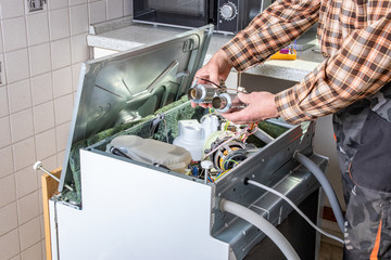 People in technician jobs. Appliance repair technician works on broken dishwasher in a kittchen....