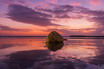 Bali Sanur at sunrise on the beach. Beautiful calm water with 2 temples on a breakwater. Great reflection in the water with backlighting and great clouds