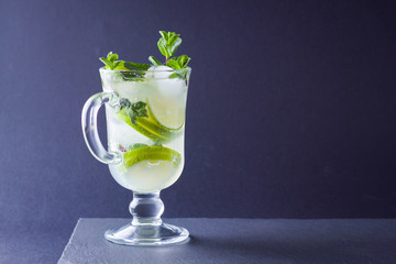 Mojito on black background. Mojito cocktail with lime and fresh mint on slate board. Summer refreshing cocktail with citrus on dark background. Copy space