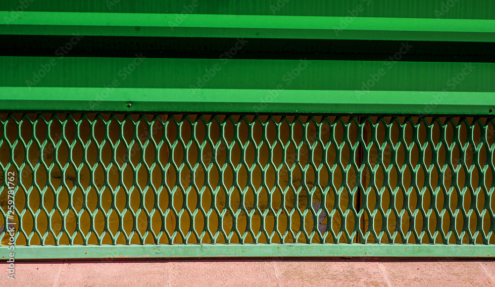 Wall mural iron old grille on down part of door. geometric holes painted by green.