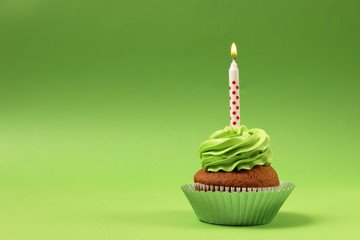  Delicious cupcake with a candle on a colored background with space to insert text. Festive...