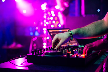hands DJ mixing and playing music on a professional controller mixer