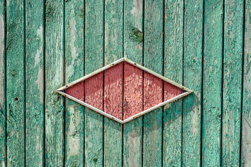 Texture of old fance, painted light-green with red rombus from wood in the centre.