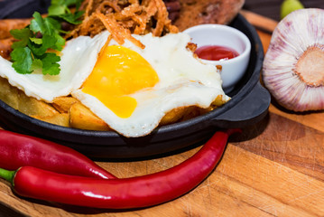 Meal with fried egg, sausages, beans, onion rings, chili pepper and sauce
