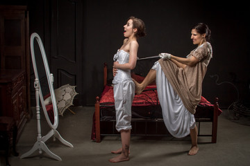 A young girl in a vintage dress tightens her corset to his girlfriend, joking format. Added a small...