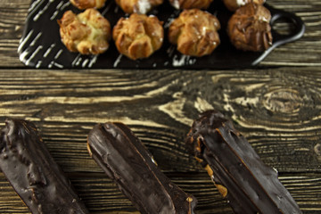 Small eclairs with cream on a wooden background