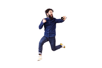 Full length portrait of a joyful bearded hipster man in glasses, jumping and taking selfie, isolated on white background