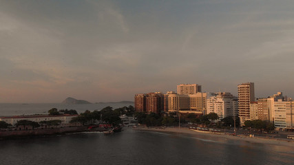 Fototapeta na wymiar Golden hour sunrise over the Copacabana fort in Rio de Janeiro with the high rise buildings catching first sunlight and islands just outside of the city coast in the background
