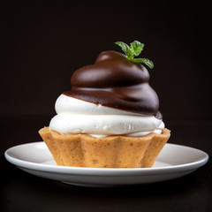 Small chocolate tarts (tartlets) with whipped mascarpone cheese on dark background