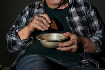 Poor senior man with bread and bowl, closeup