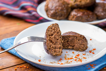 piece of cut cutlet  stuffed on a fork with vegetables and greens on the background