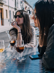 Young and beautiful friends having a refreshing drink on a terrace of a day bar