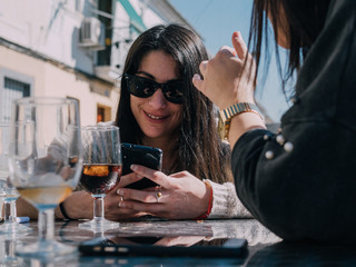 Young and beautiful friends having a refreshing drink on a terrace of a day bar