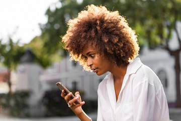 Outdoor portrait of a Young black African American young woman texting  on mobile phone