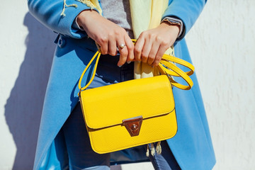 Young woman holding stylish handbag and wearing trendy blue coat. Spring female clothes and accessories. Fashion