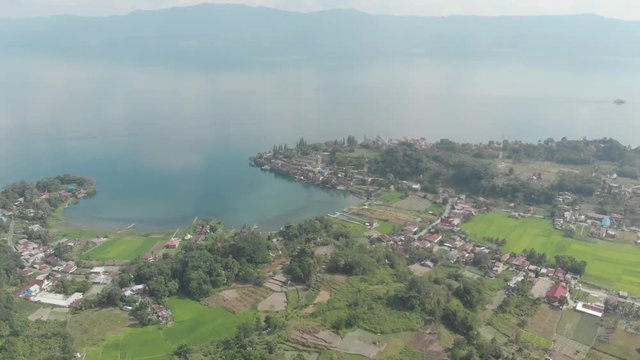Aerial: lake Toba and Samosir Island from above Sumatra Indonesia. Huge volcanic caldera covered by water, Batak villages, green rice paddies, equatorial forest. Native cinelike D-log color profile.