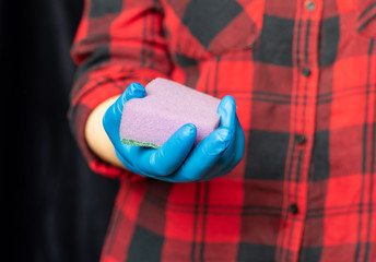 Fototapeta premium Kitchen sponge in the hand of the girl. Girl's hand in a hygienic glove.