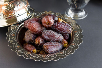 Big size,luxury dried date fruits in the stylish copper bowl on the black surface.Ramadan concept.
