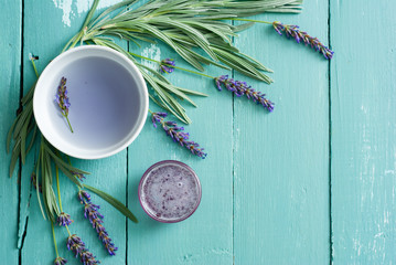 cup of lavender tea, flowers and syrup on blue wooden table background