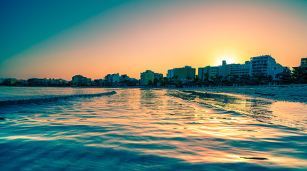 Wavy curves  of  sea is covered  in golden sunset light. Sea at sunset sunlight. Wavy curves pattern on beach.   Waves in bokeh focud