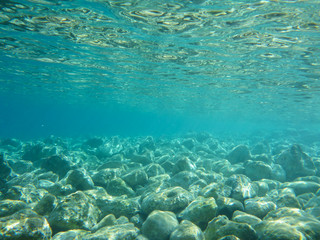 Naklejka na ściany i meble UNDERWATER view of turquoise clear water and white pebbles scattered off the seabed of the Antisamos bay, Kefalonia island, Ionian Sea, Greece.