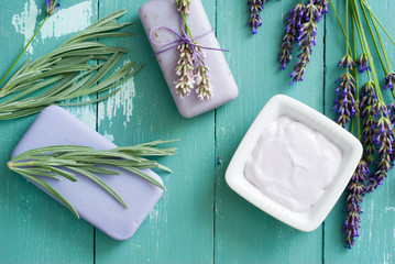 lavender soaps and cosmetic cream, flowers on blue wooden table