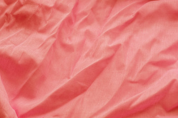 Coral background from a textile material with wicker pattern, closeup. Cloth backdrop. Crumpled fabric. Selective focus