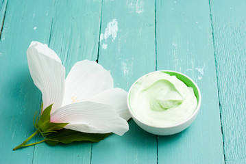 cosmetic cream and white mallow flower on blue wood table