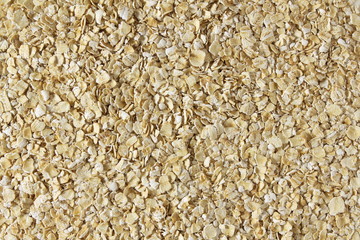 Dry rolled oatmeal flakes as background top view