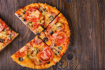 Piece torn off tasty pizza and cooking ingredients tomatoes basil on wooden background. Top view of hot pizza. With copy space for text. Flat lay. Banner
