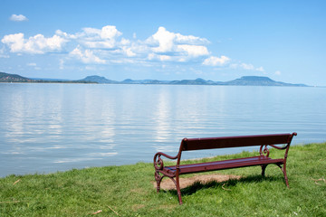 Bench at the beach of lake Balaton with the Badacsony mountains in the background in Hungary