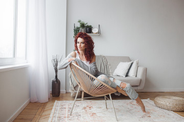 Very attractive young woman indoors. Portrait of curly haired female. Redhaired beautiful woman at home.