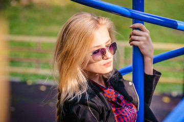 Cheerful attractive girl in sunglasses on the Playground in the Park.