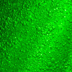 Light beam rays through three dimensional green fluid with transparent air bubbles.