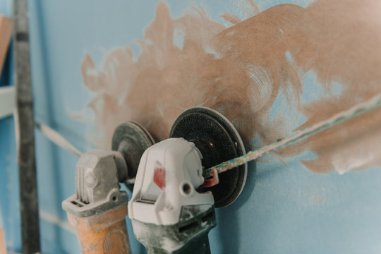 Closeup dirty grinders hanging on twist near blue wall with brown blots