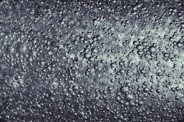 Silver metallic paint over bumpy surface, abstract texture photo.