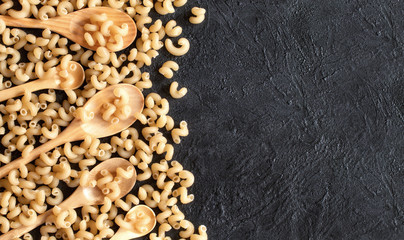 pasta on the table and in wooden spoons top view. background of not cooked pasta on the table.