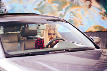 Attractive girl with glasses driving a car, irritated by traffic jams.