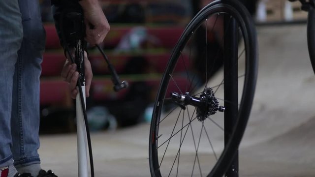 Well-groomed handsome master , specialist in bicycles, repairing a bicycle in his workshop, wheels, frame, spokes. Concept: pro bike, cycle passion, lifestyle. Master pumps the wheel from the bike pum