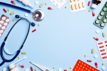 Obraz premium Cold medicine, thermometer and phonendoscope on a blue background.