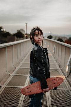 Girl with skateboard on walkway