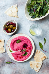 Pink beet hummus spread or dip with mix salad leaves. Healthy raw summer appetizer, vegan, vegetarian snack.