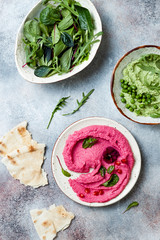 Green pea and pink beet hummus spread or dip with mix salad leaves. Healthy raw summer appetizer, vegan, vegetarian snack.