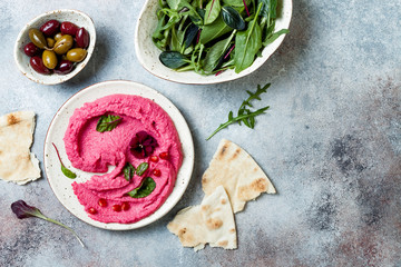 Pink beet hummus spread or dip with mix salad leaves. Healthy raw summer appetizer, vegan, vegetarian snack. Copy space